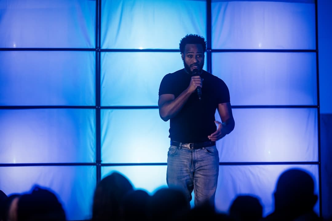 Conference presenter speaking into a wireless handheld microphone on a professional stage